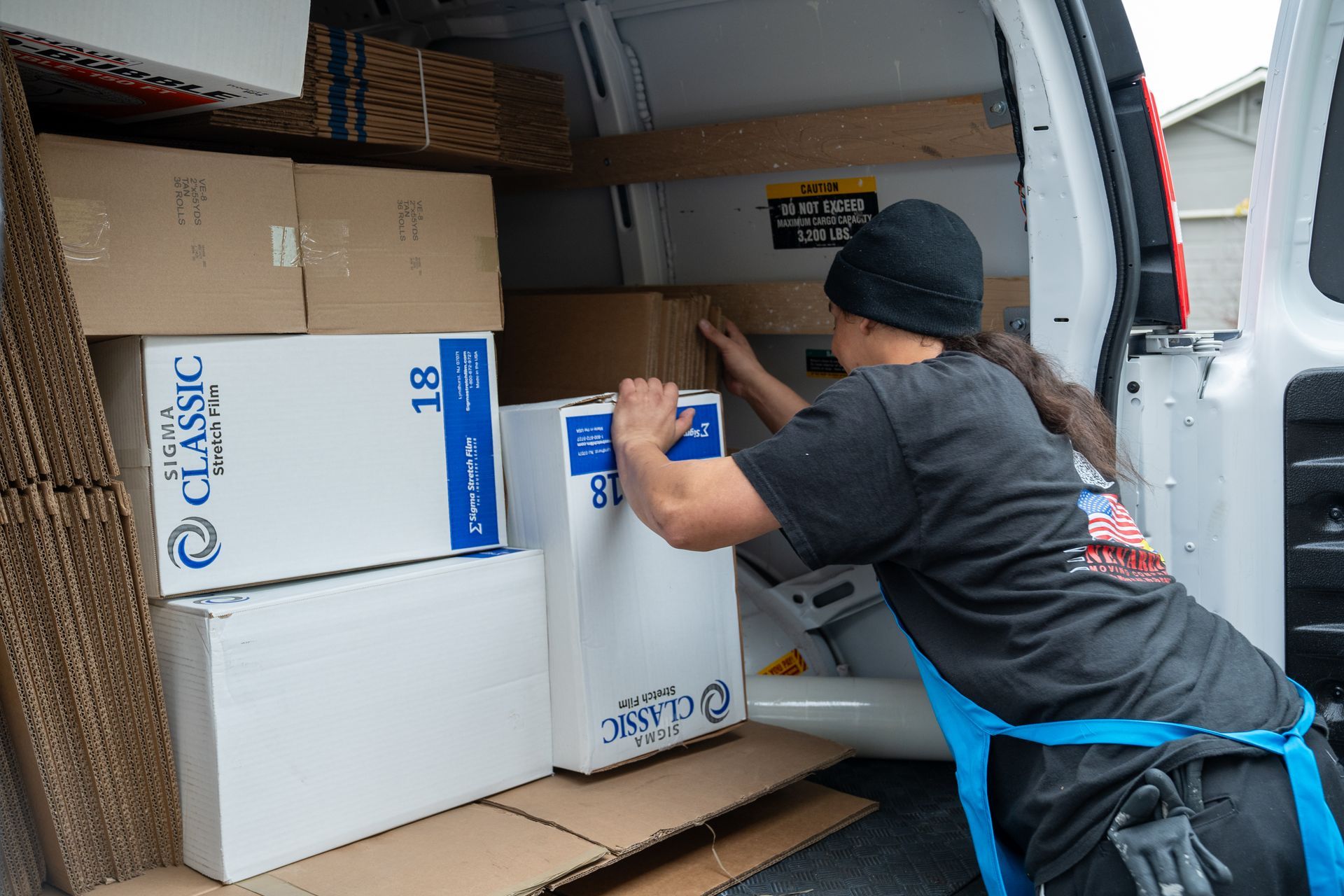 A man is loading boxes into the back of a van.