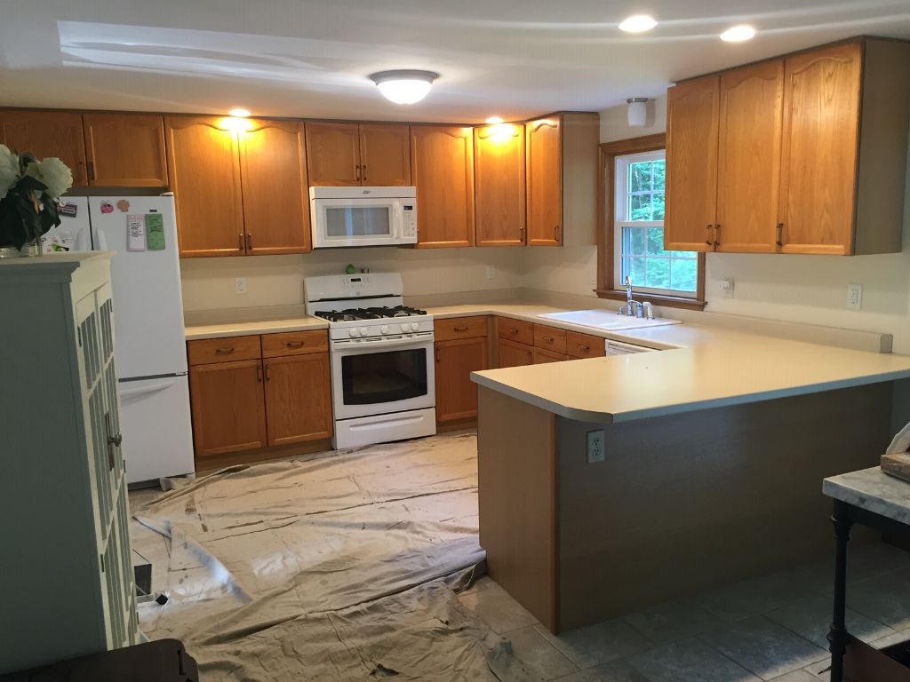 A kitchen with wooden cabinets , a stove and a refrigerator.