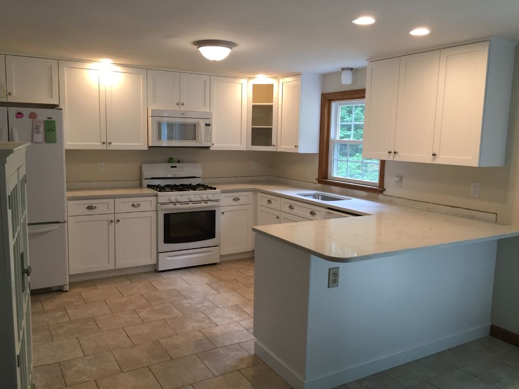 A kitchen with white cabinets a stove and a refrigerator