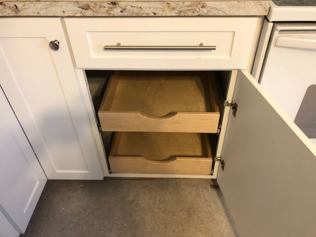 A kitchen cabinet with drawers pulled out of it