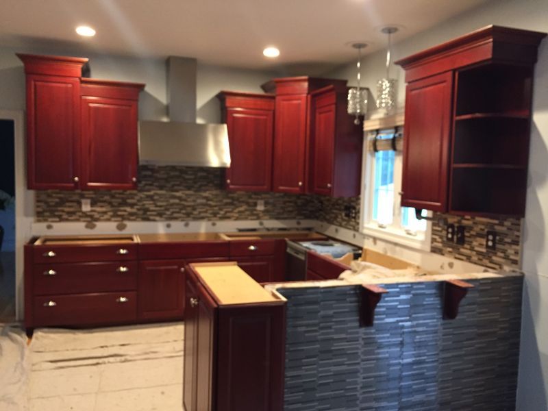 A kitchen with red cabinets and white counter tops