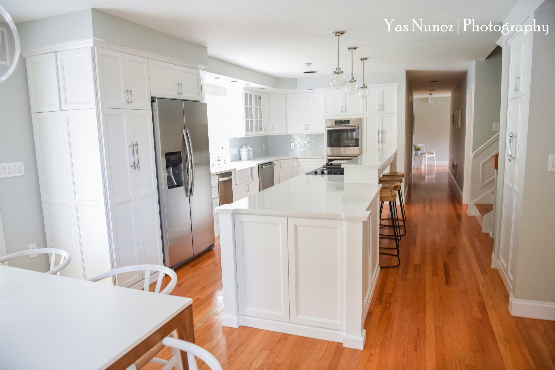 A kitchen with white cabinets and stainless steel appliances and a large island in the middle.