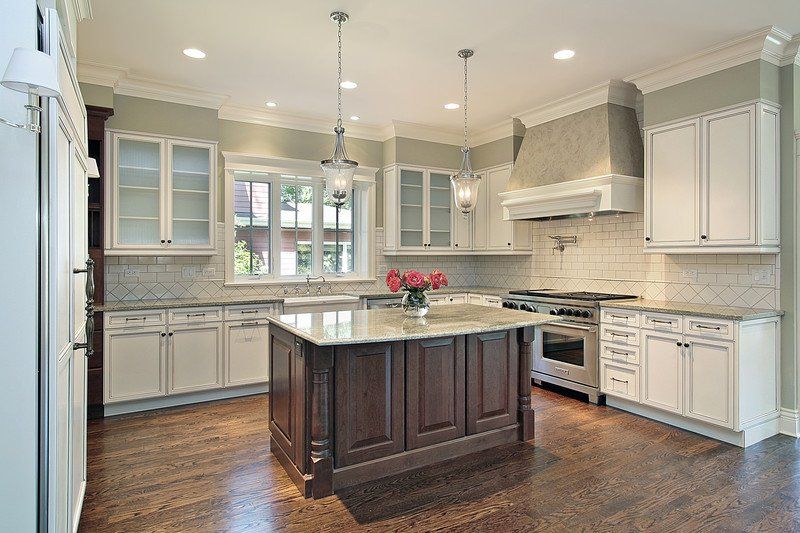 A kitchen with white cabinets and a large island in the middle.