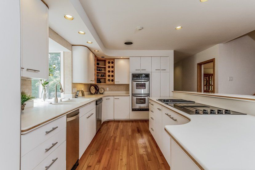 A kitchen with white cabinets and hardwood floors