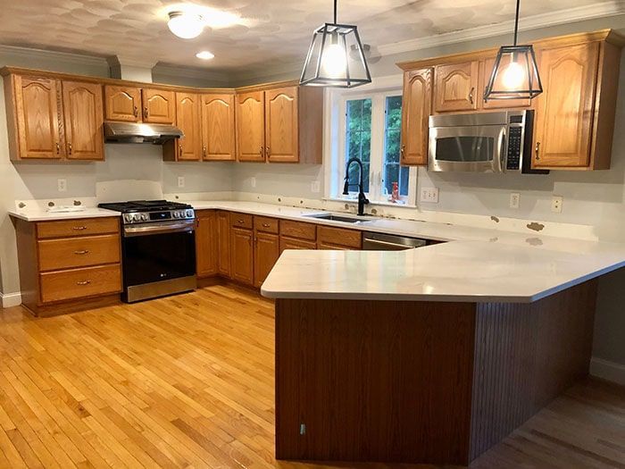 A kitchen with wooden cabinets , stainless steel appliances , and a large island.