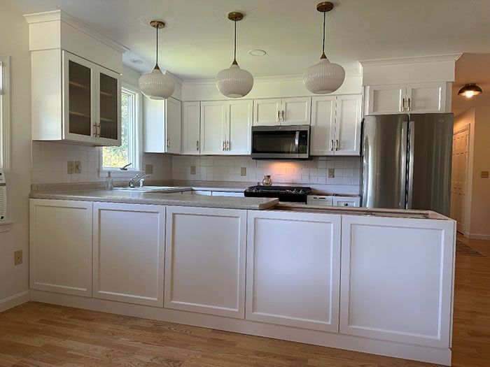 A kitchen with white cabinets and a stainless steel refrigerator.