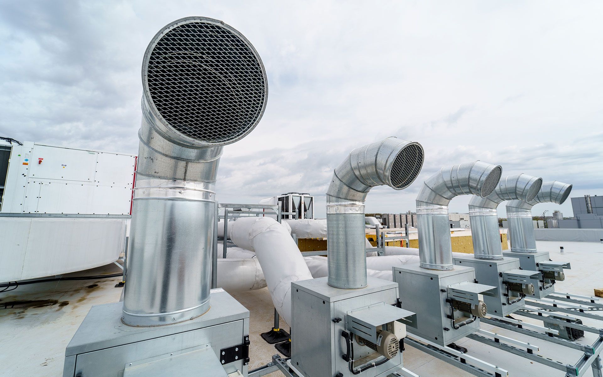 Rooftop HVAC units with large metal vents under an overcast sky.