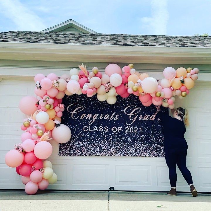 A woman is decorating a sign that says congrats grad class of 2021.