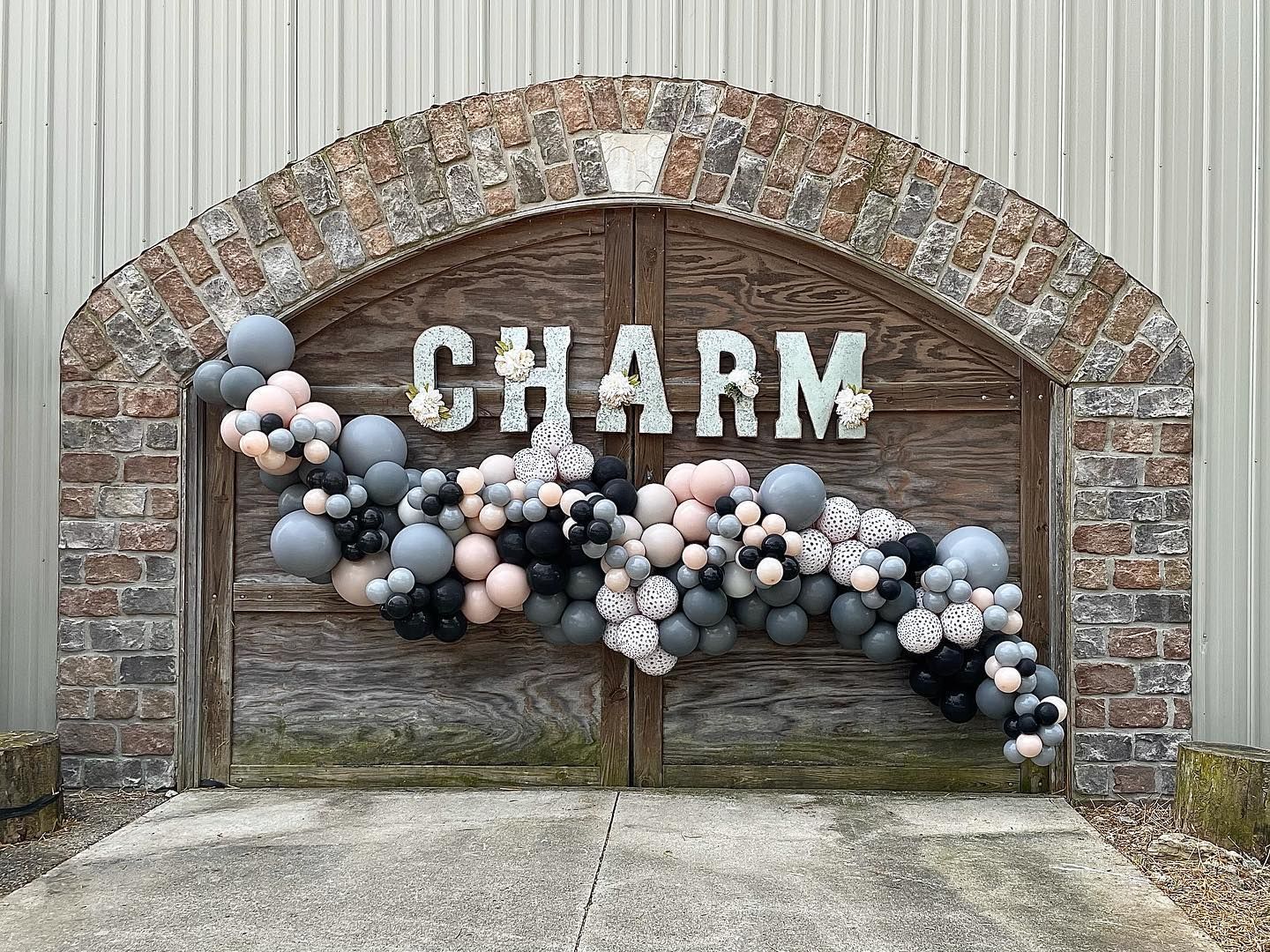 A brick wall with balloons hanging from it.