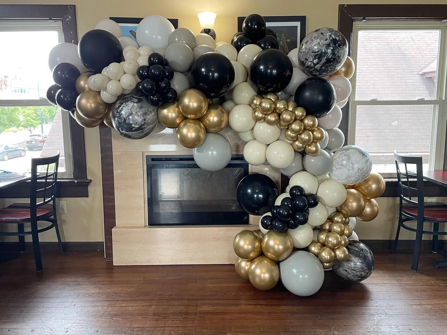 A bunch of balloons are sitting in front of a fireplace in a room.