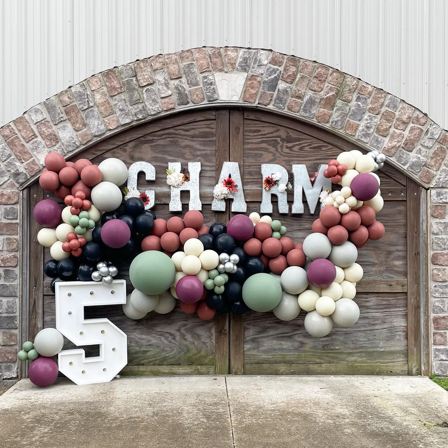 A brick wall with balloons and the word charm on it.