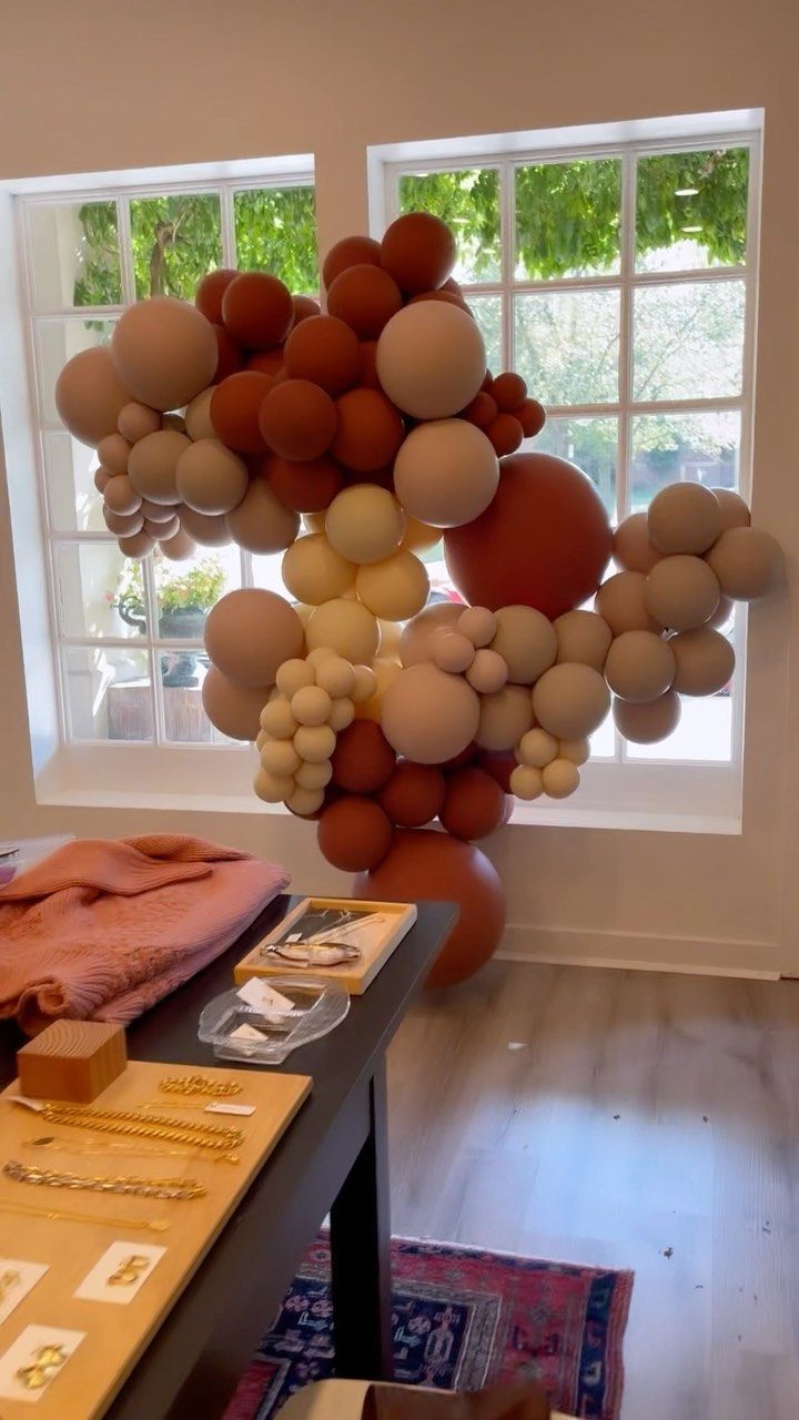 A bunch of balloons are sitting on a table in front of a window.