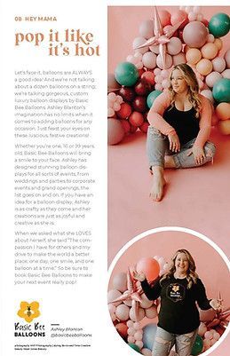 A woman is sitting on the floor in front of a wall of balloons.