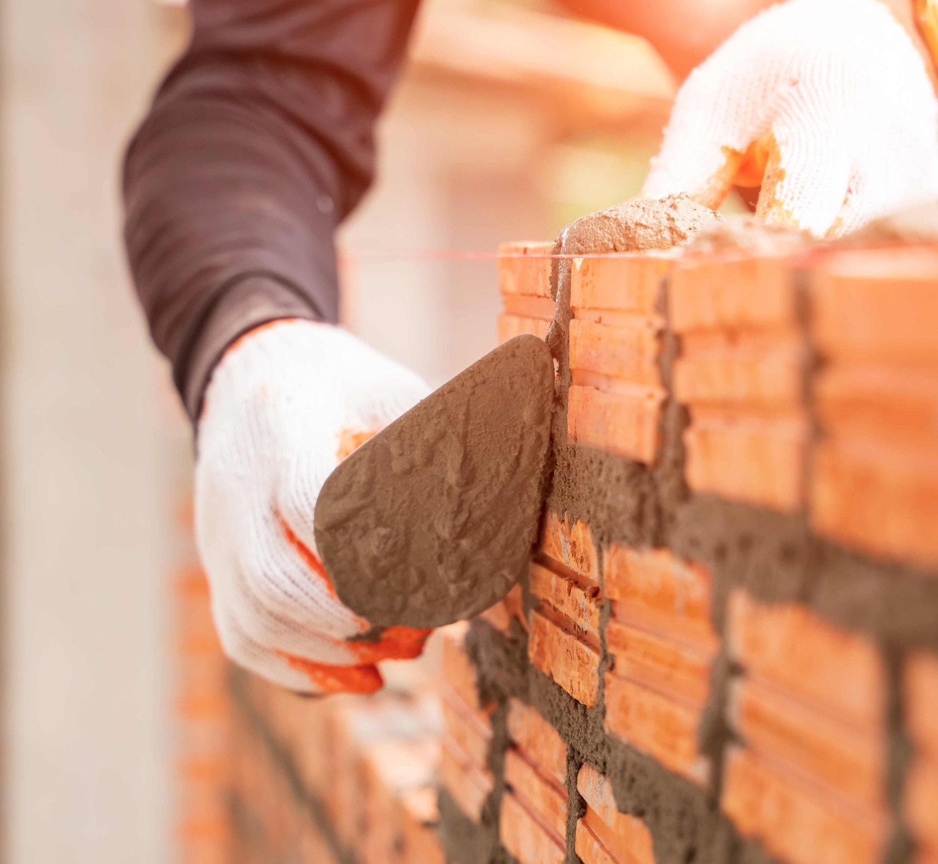 A man is laying bricks on a wall with a trowel.