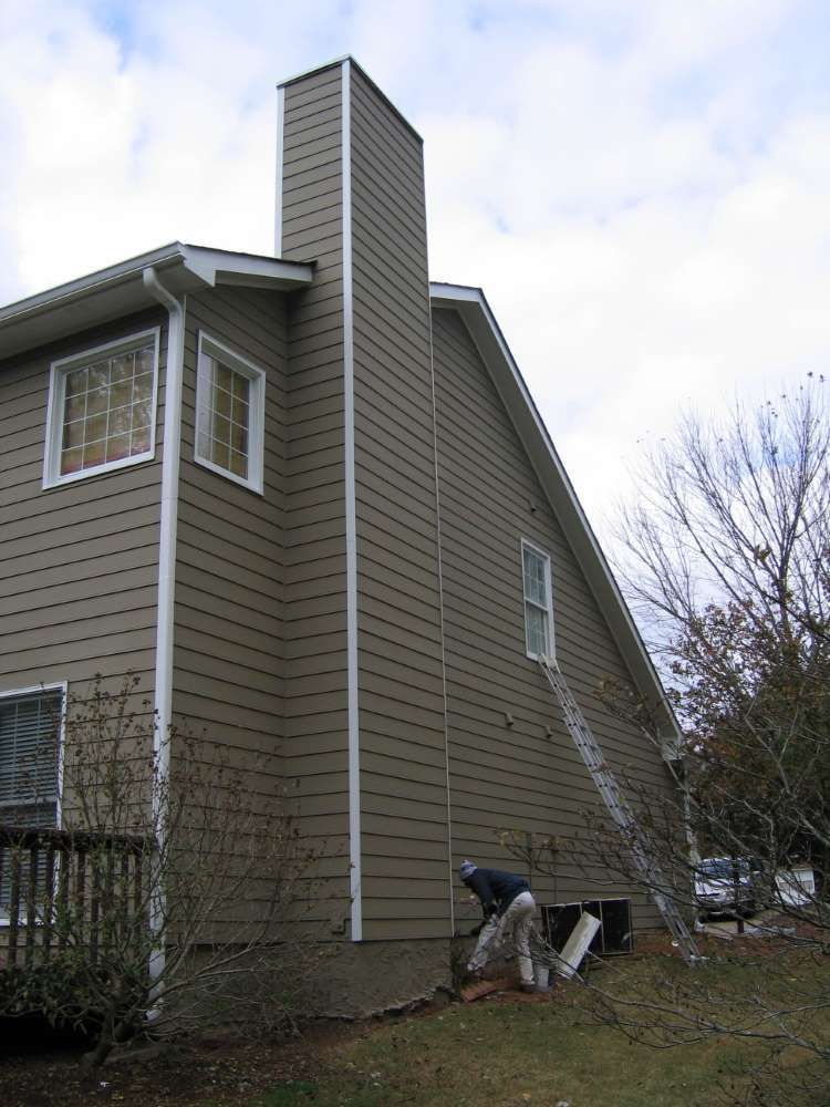 A man is working on the side of a house