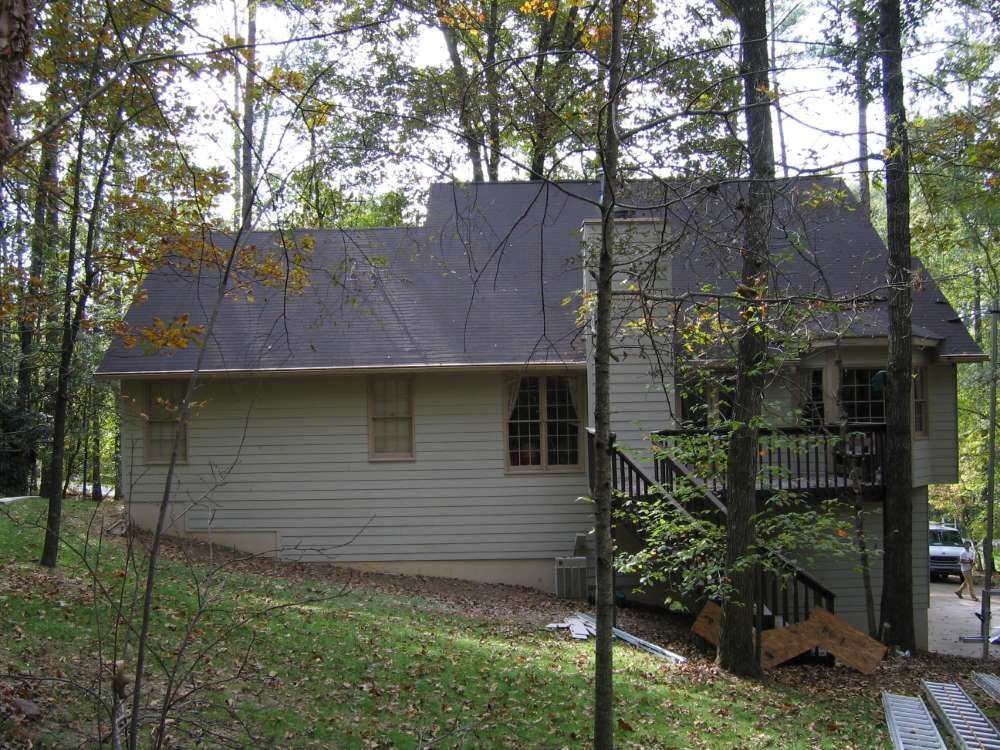 A house with a black roof is surrounded by trees