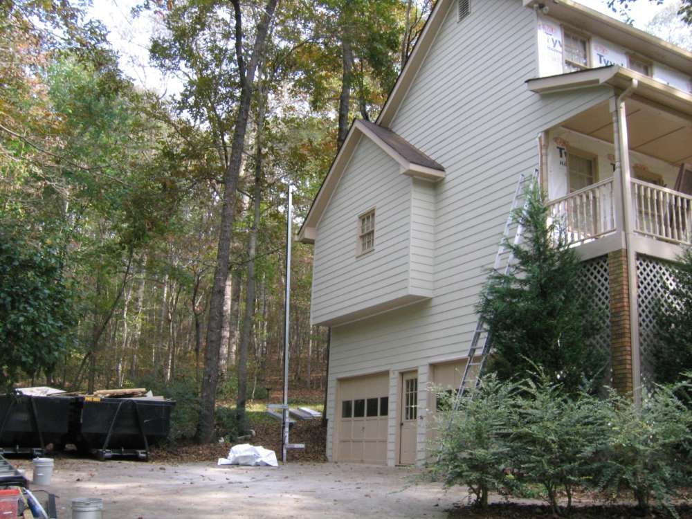 A house with a garage and a porch is surrounded by trees