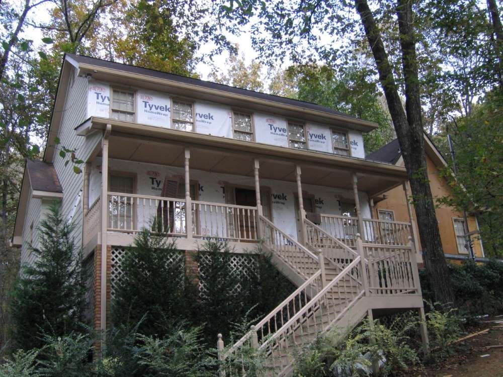 A house with a porch and stairs has styrofoam on the roof