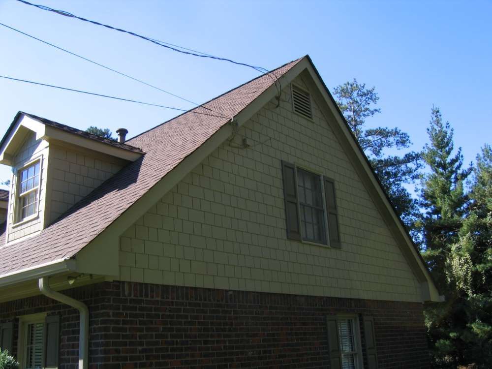 A brick house with a brown roof and shutters