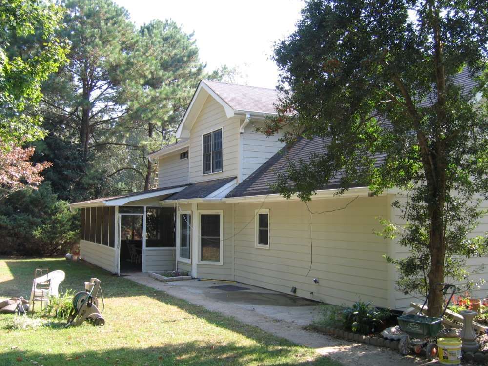 A white house with a black roof and a screened in porch