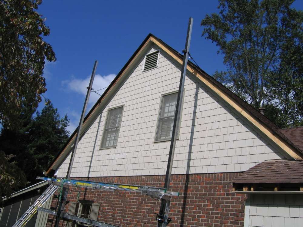A brick house with a white siding is being painted
