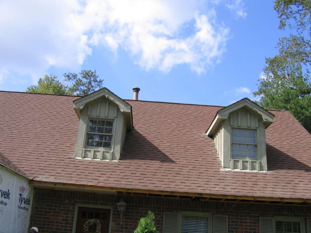 A brick house with a brown roof and two windows