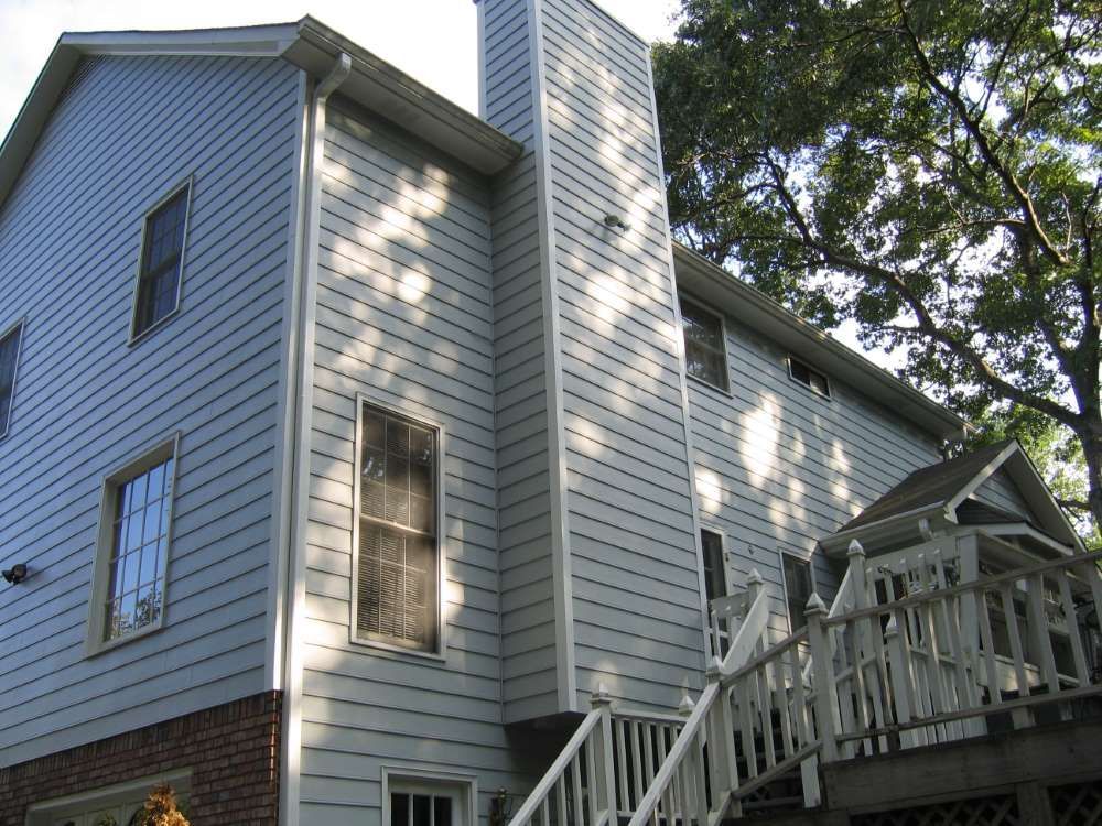 A white house with stairs leading up to a deck
