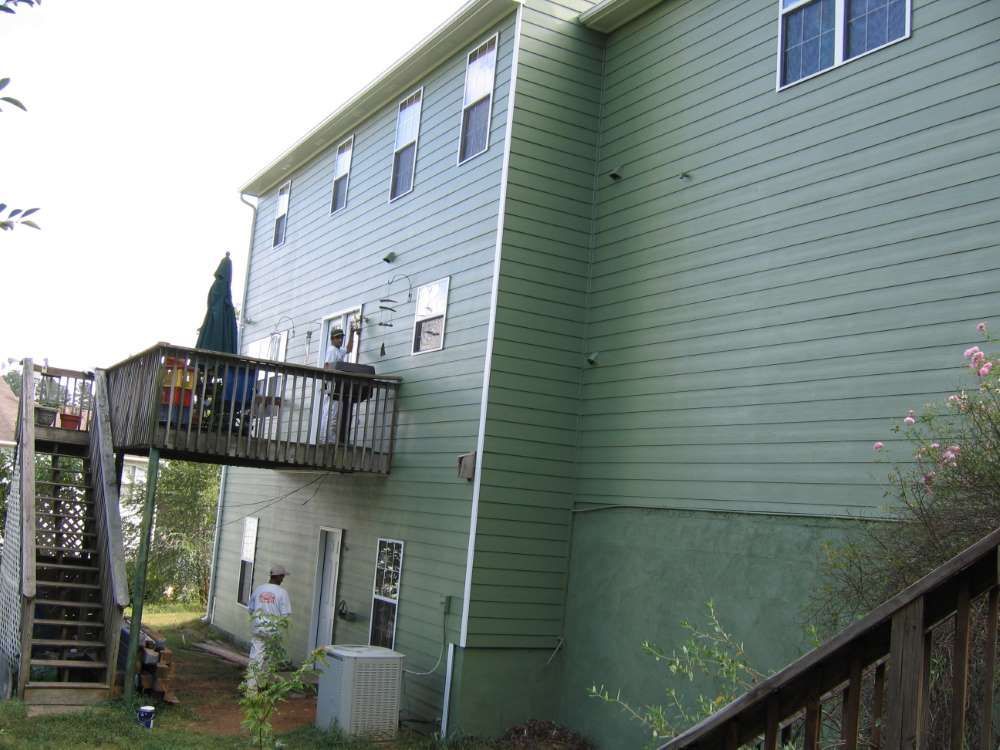 A green house with a deck and stairs leading up to it