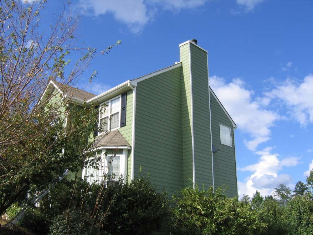 A green house with a chimney on top of it