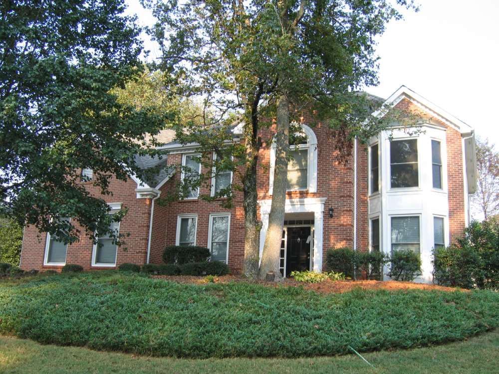 A large brick house with a lush green lawn in front of it