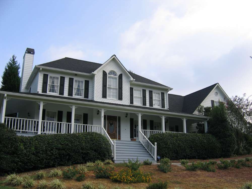 A large white house with black shutters and a large porch