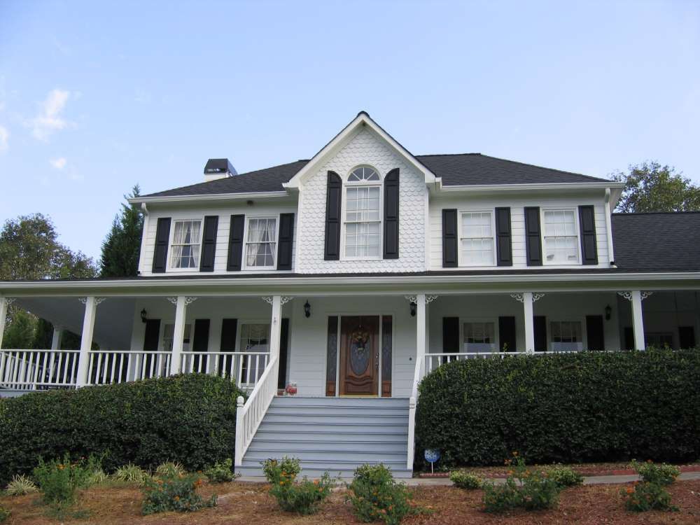 A large white house with black shutters and a porch