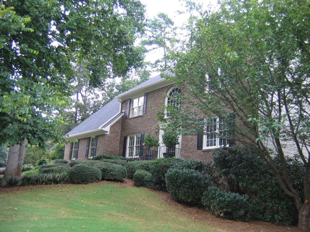 A large brick house with a blue roof and black shutters