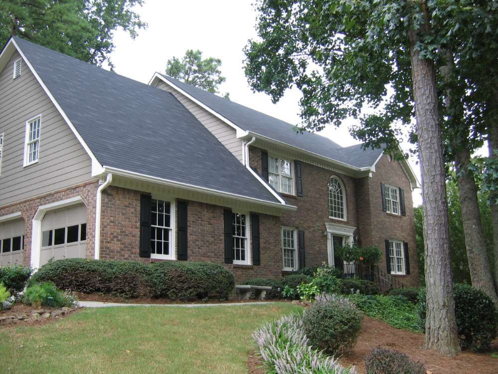 A large brick house with a black roof and white trim