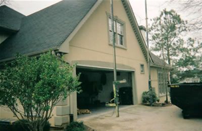 A house with a garage and a dumpster in front of it