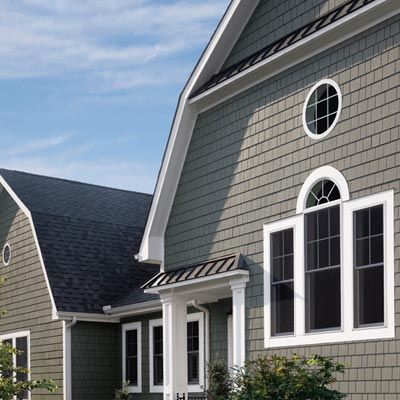 A gray house with a black roof and white windows