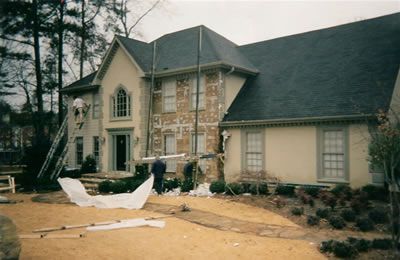 A large house with a black roof is being painted