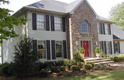 A large white house with black shutters and a red door