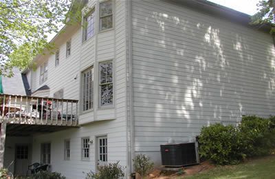 The back of a white house with a deck and a lot of windows.