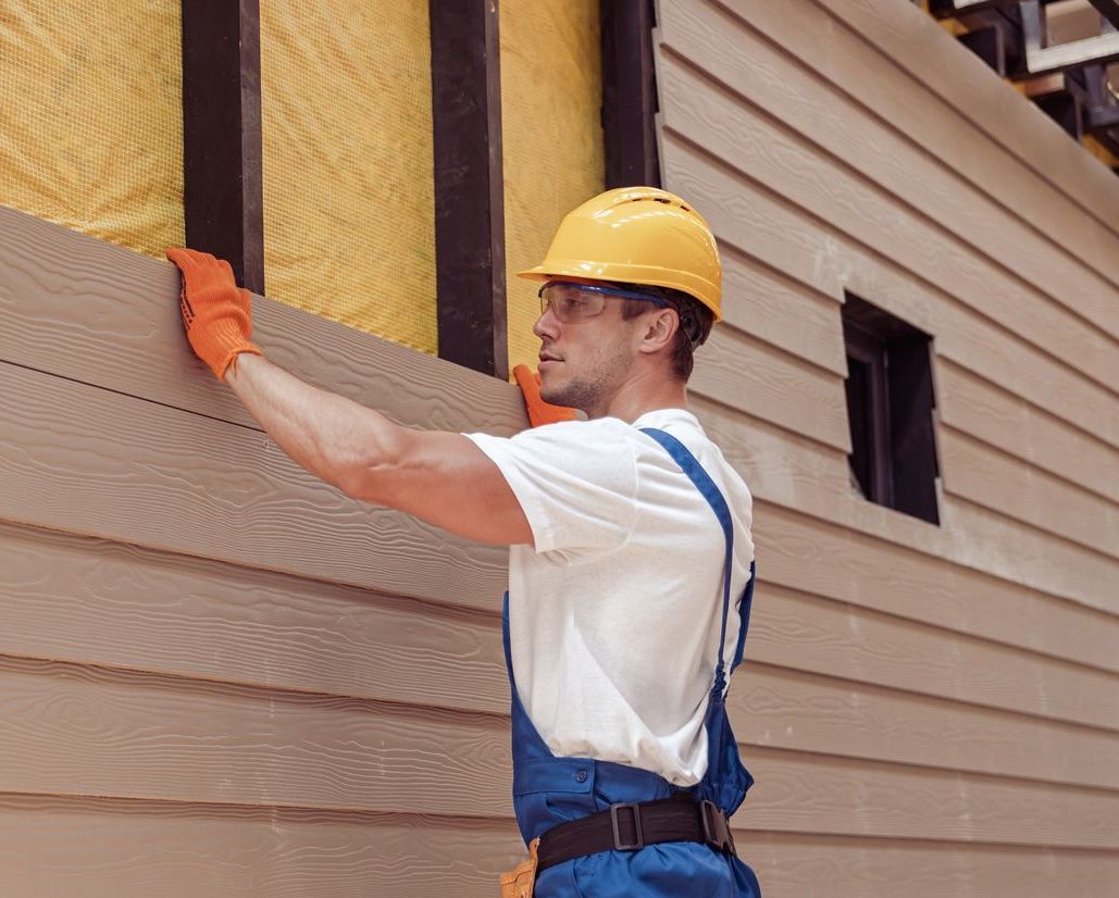 A man is installing siding on a house.