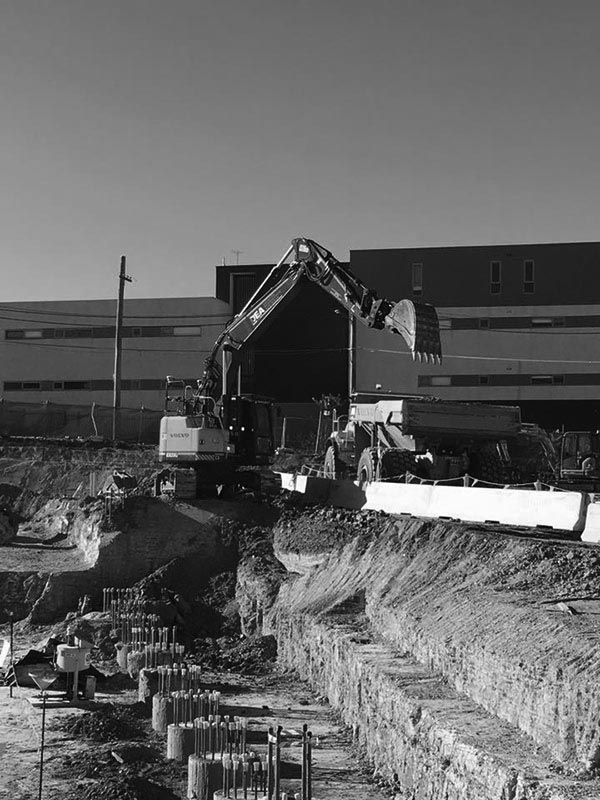 A black and white photo of a construction site with a large building in the background.