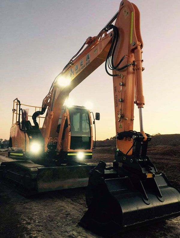 A large orange excavator is parked on a dirt road