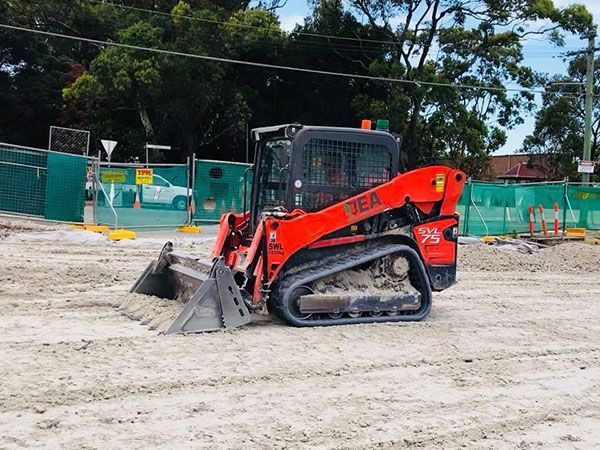 A Kubota skid steer is moving dirt on a construction site