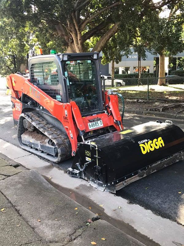 A red and black Kubota skid steer parked on the side of the road