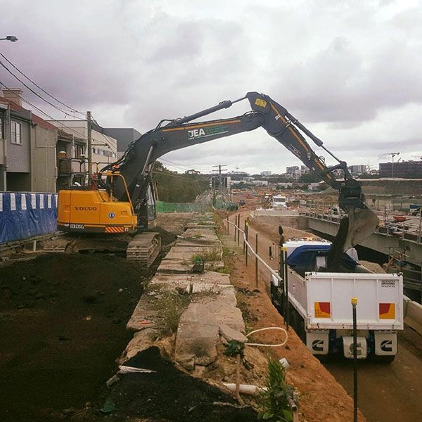 A yellow excavator is loading dirt into a dump truck
