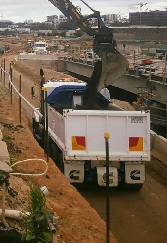 A dump truck being loaded with dirt on a construction site