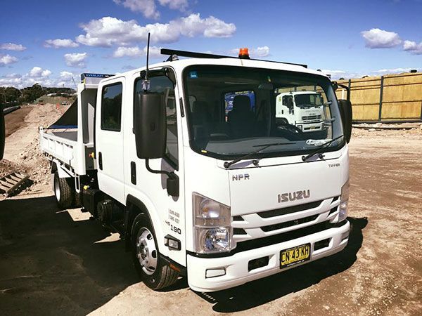 A white tipper
 truck is parked in a dirt lot