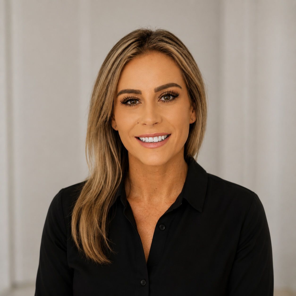 Portrait of a smiling woman in a black blouse against a light curtain background