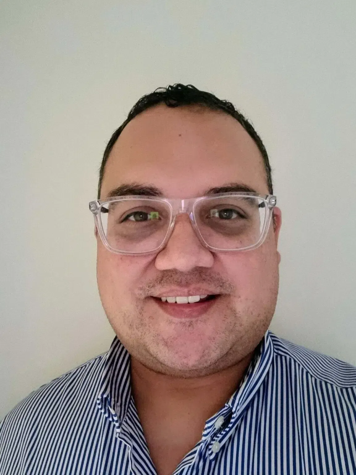 Man wearing glasses and striped shirt smiles, looking at camera.