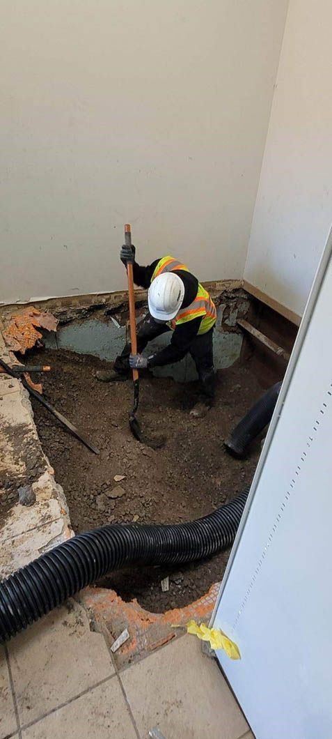 A man is kneeling down in a room holding a shovel.